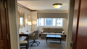Een hotelkamer met een bureau, stoel, bank en een bijzettafeltje.