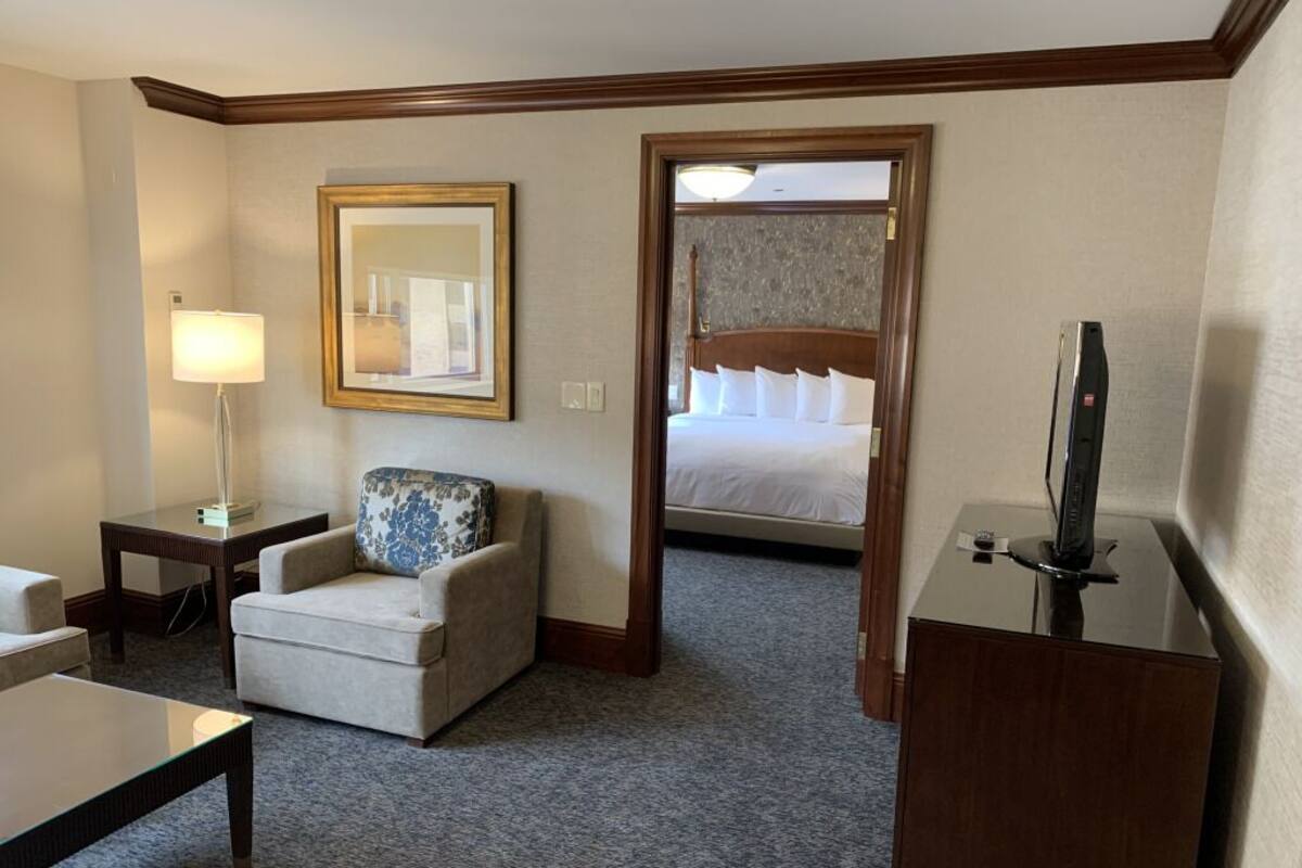 Una habitación de hotel con una cama, una silla, un escritorio, una lámpara y un televisor.