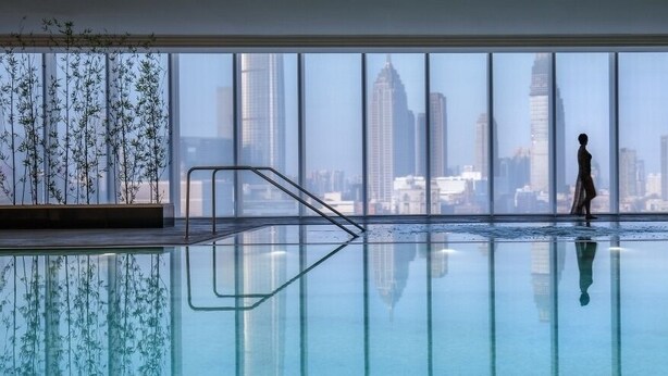 Una piscina interior moderna con vistas a la ciudad a través de amplios ventanales.