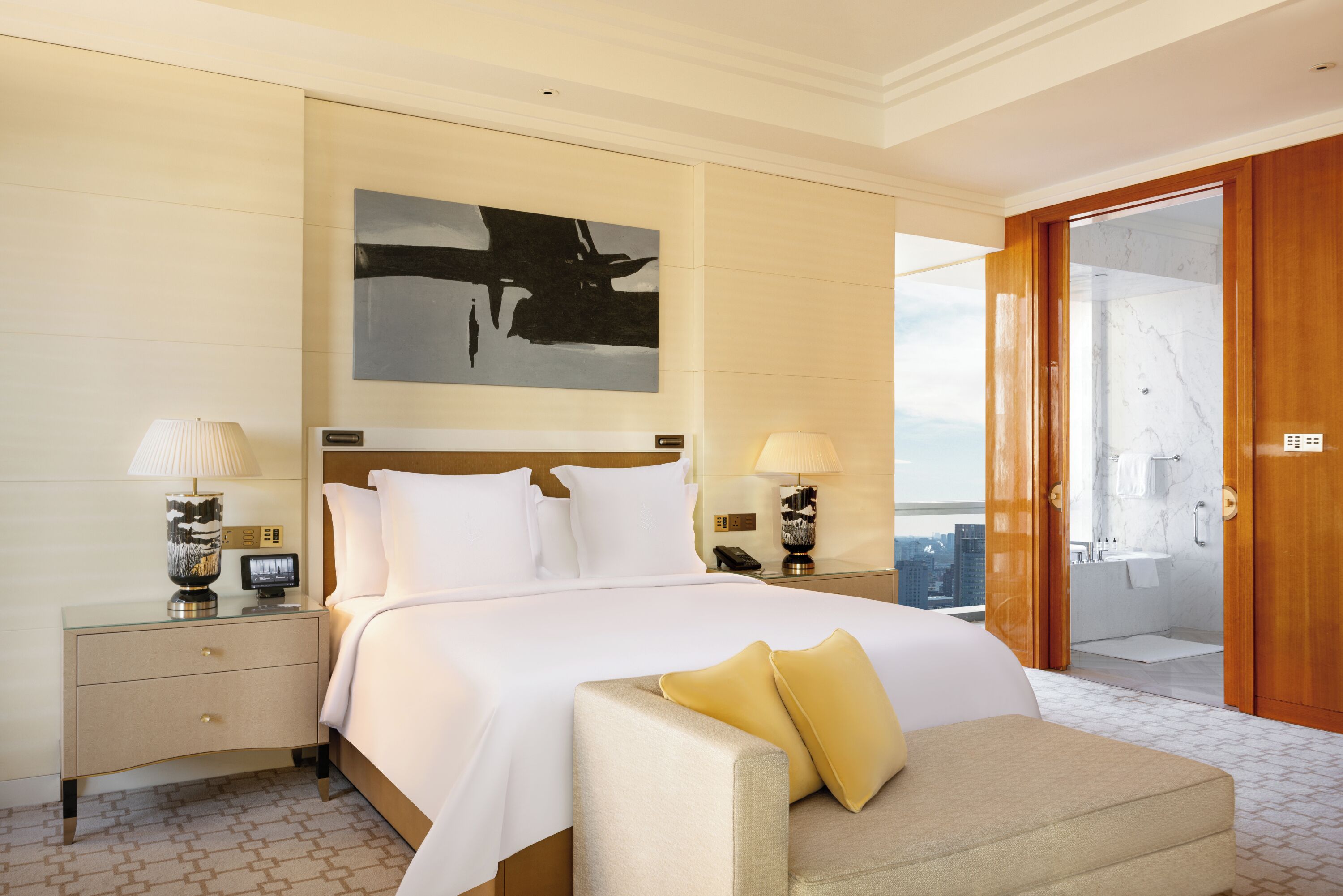 Habitación de hotel con una cama grande, mesitas de noche, un sofá y vistas a la ciudad.