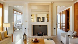 Un salón amplio con chimenea, un comedor con una mesa preparada para dos personas, y vistas de la ciudad a través de grandes ventanales.