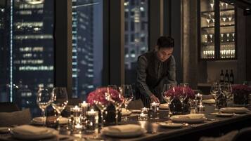 A well-set dining table with candles, glasses, and a city view.