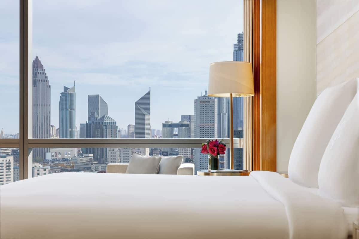 Habitación de hotel con un amplio ventanal y vistas al horizonte urbano.