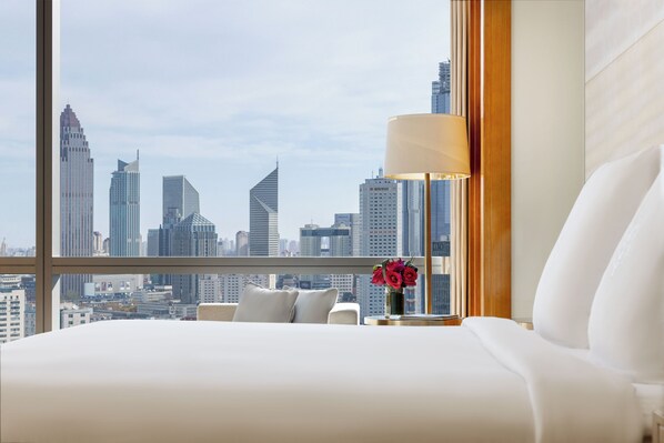 A hotel room with a large window offering a city skyline view.