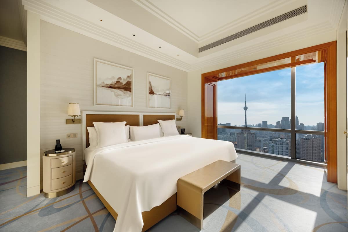 Una habitación de hotel moderna con una cama grande, una mesita de noche y vistas a la ciudad.