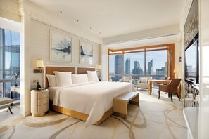 Amplia habitación de hotel con una cama grande, un escritorio y vistas a la silueta urbana.