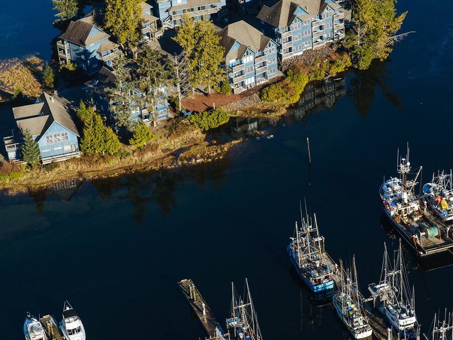 An aerial view of a waterfront property with multiple buildings and a marina with various boats.