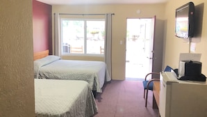 A hotel room with two beds, a television, a desk, and a window with curtains. - Laurel Park Inn (Maggie Valley)
