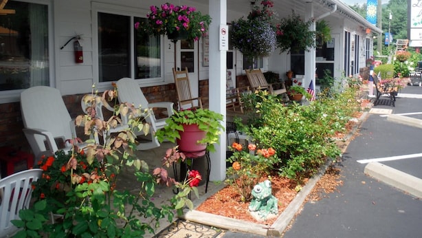 A motel with outdoor seating, potted plants, and a fire extinguisher. - Laurel Park Inn (Maggie Valley)