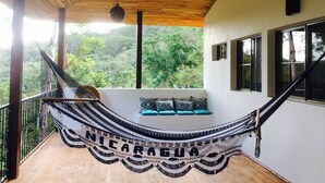 A hammock with "NICARAGUA" written on it, a wooden ceiling, a view of trees, and a staircase. - Chez Nous B&B (San Juan del Sur)