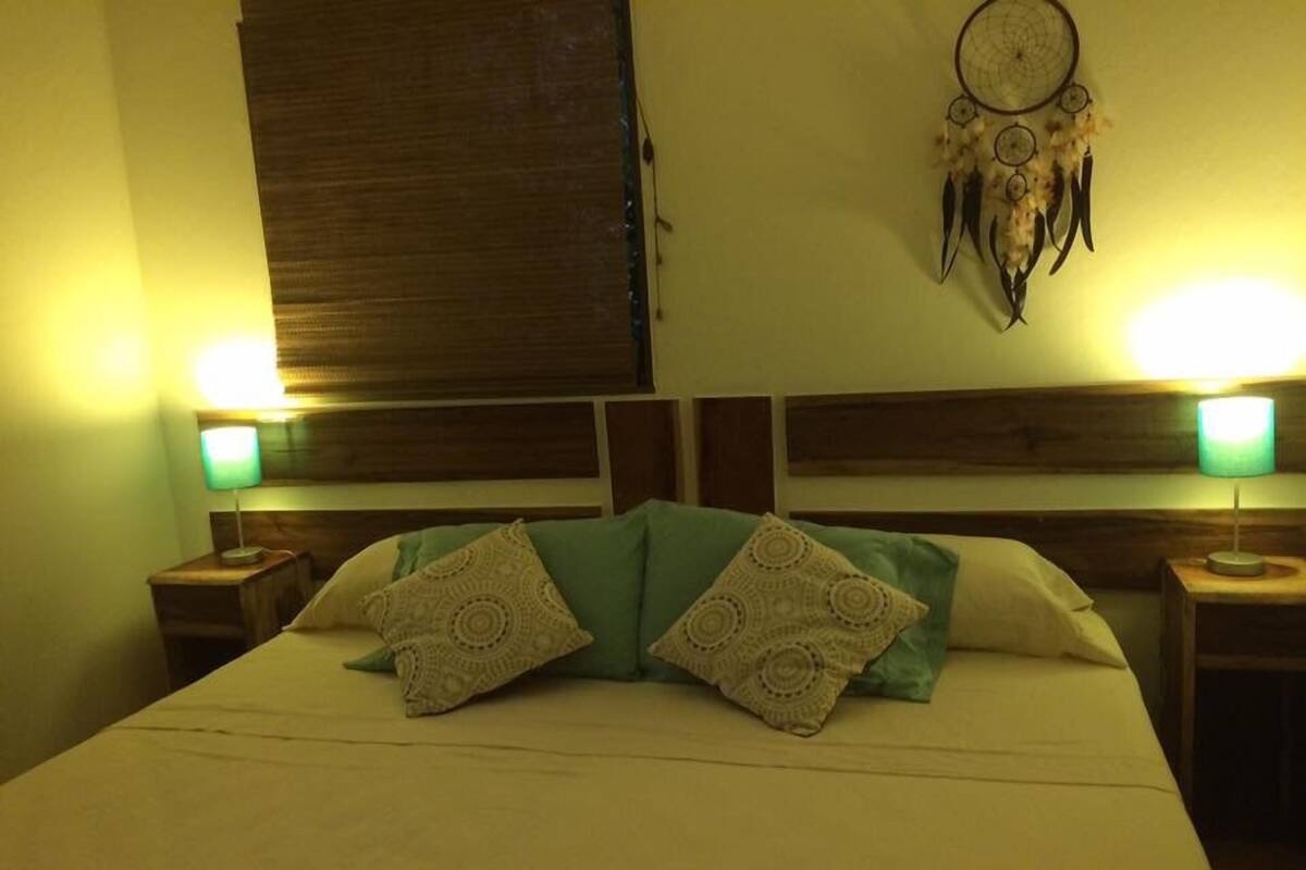 Un lit avec deux oreillers, une tête de lit en bois et deux lampes de chevet.