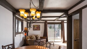 A dining area with a wooden table and chairs, a sofa, and a chandelier. - The Landing at Estes Park - Riverside Retreat (Estes Park)