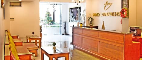 Un área de recepción con mostrador de madera, una zona de estar con bancos y un ventanal con vistas a zonas verdes.