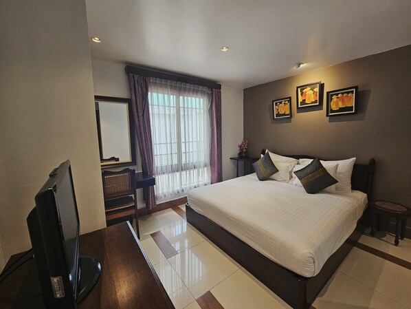 A bedroom with a large bed, a TV, a desk, and a window with curtains. - Family Boutique Hotel (Vientiane)
