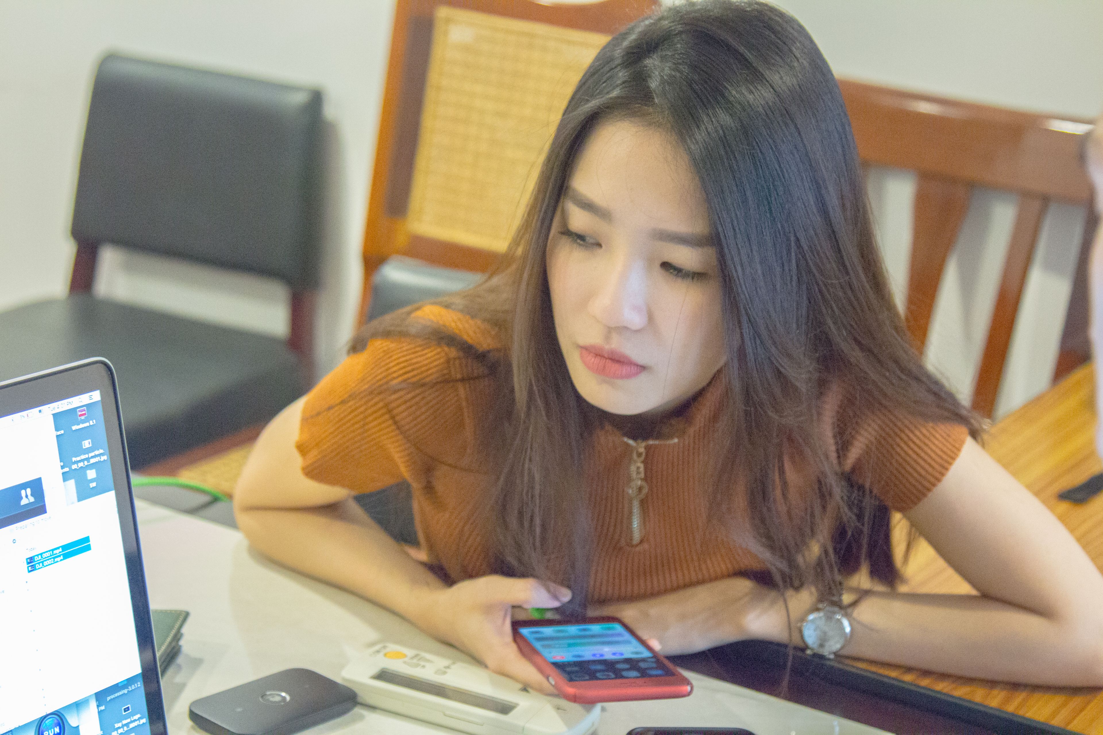 A person sitting at a table with a laptop, a smartphone, and a calculator.