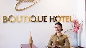 A reception desk with a sign reading "BOUTIQUE HOTEL" and a decorative gold sign above it. - Family Boutique Hotel (Vientiane)