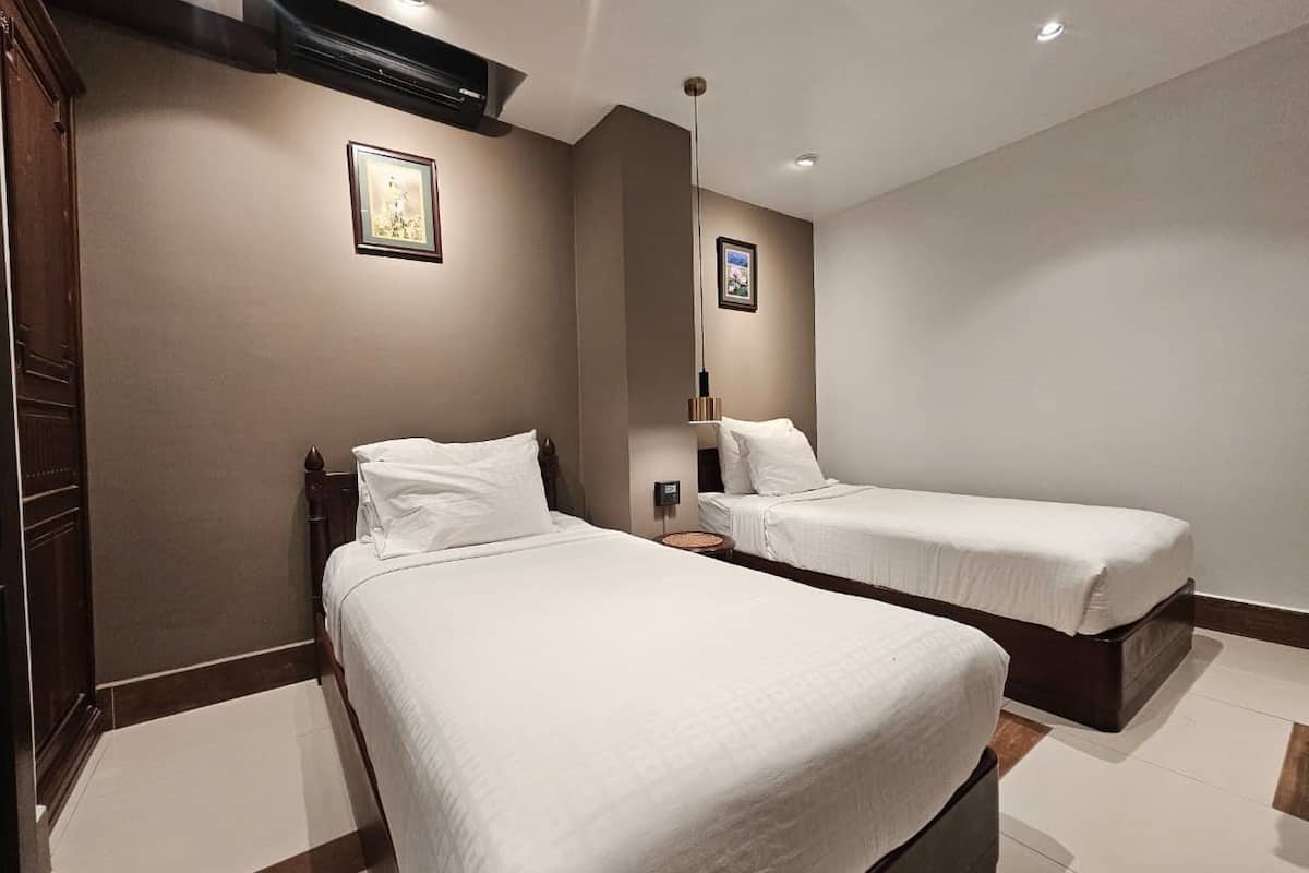 Une chambre d’hôtel avec deux lits, une armoire en bois et un tableau encadré au mur.