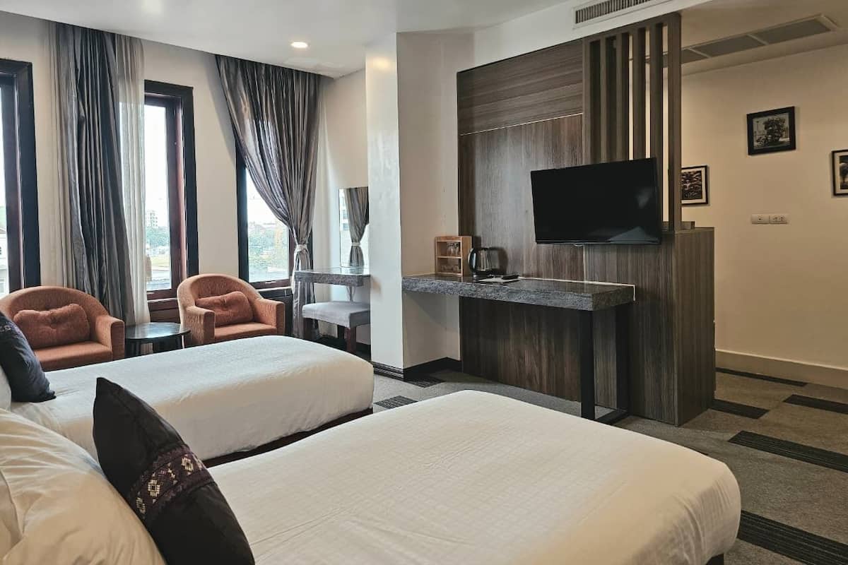 Une chambre d’hôtel avec deux lits, un téléviseur à écran plat, un bureau avec une machine à café et une vue sur l’extérieur grâce à de grandes fenêtres.