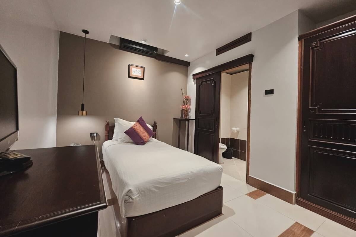 Une chambre d’hôtel avec un lit, une table de chevet et une armoire.