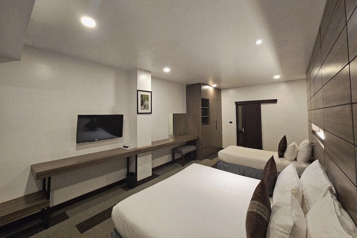 Une chambre d’hôtel équipée d’un lit, d’un bureau, d’une télévision et d’une armoire.