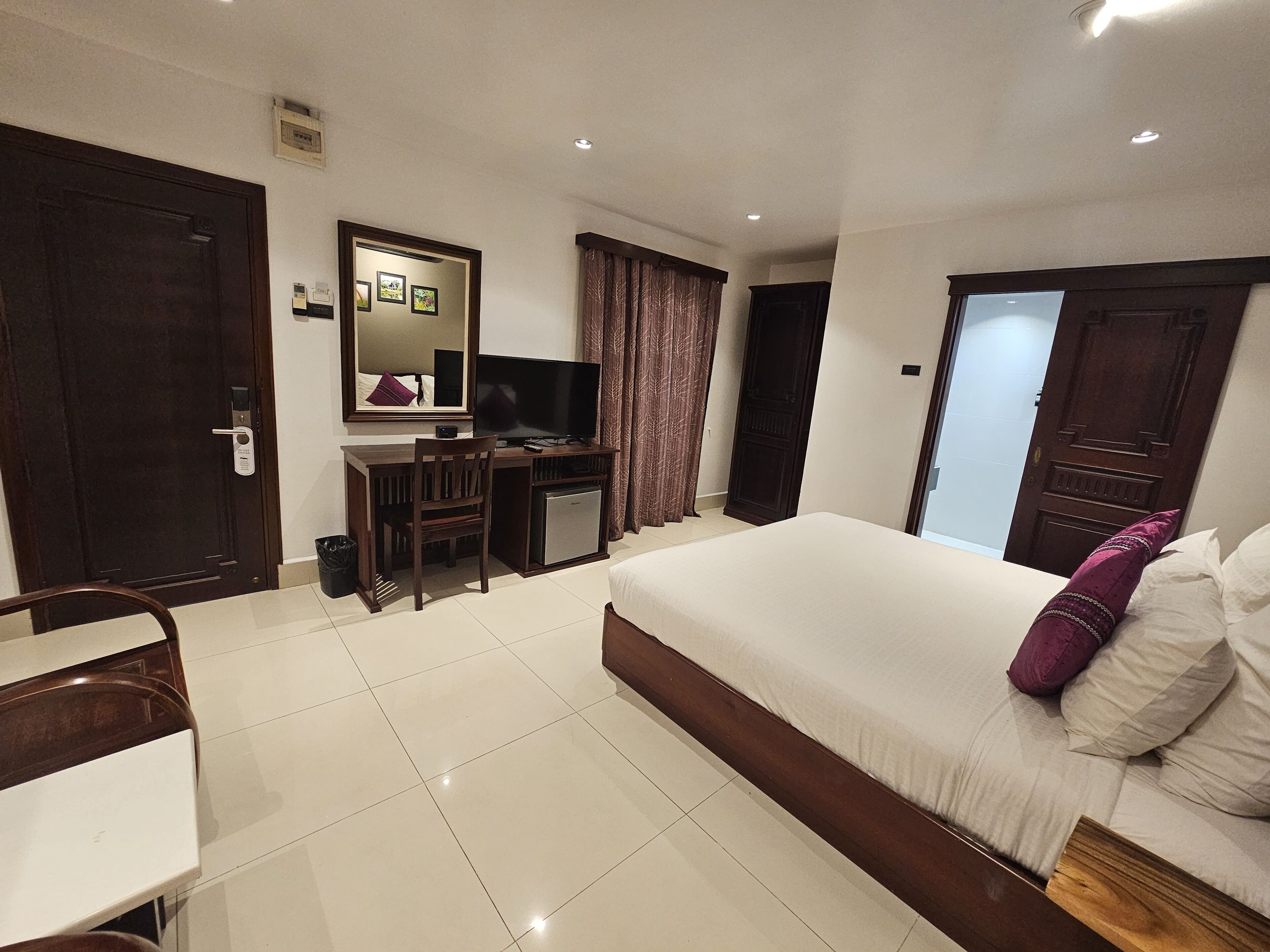 A hotel room with a bed, a desk, a television, and a small refrigerator.