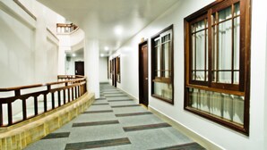 A corridor with a carpeted floor, wooden railings, and large windows with wooden frames. - Family Boutique Hotel (Vientiane)