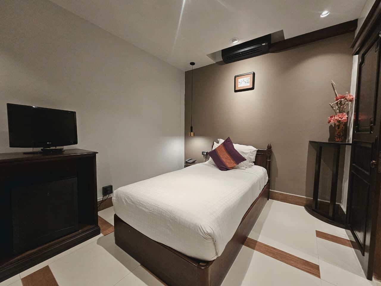 Una habitación de hotel con cama, televisión, mesita de noche y cómoda.