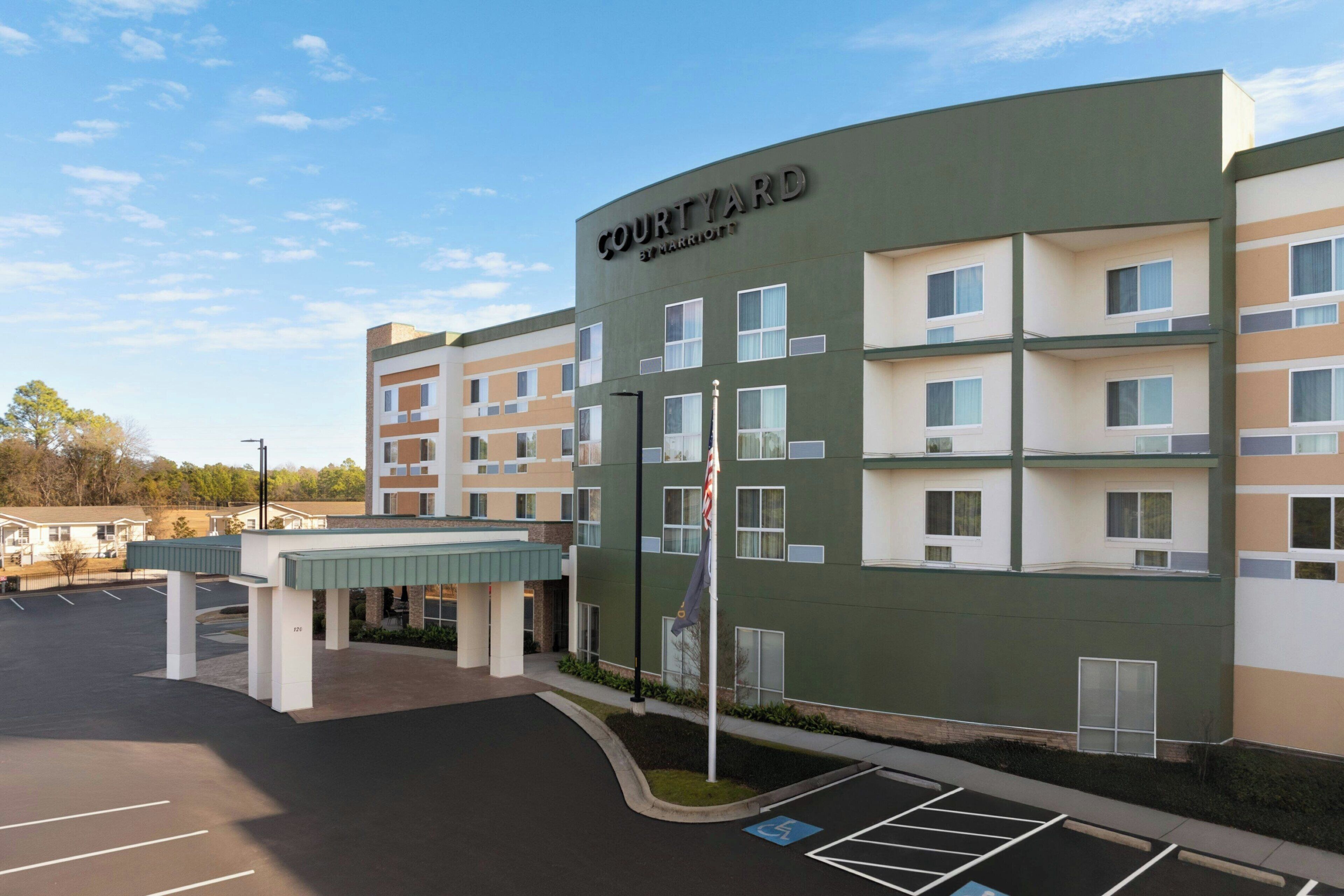 A Courtyard by Marriott hotel with a parking lot and a covered walkway.