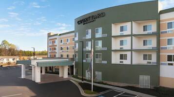 A Courtyard by Marriott hotel with a parking lot and a covered walkway.