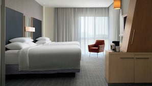 A modern hotel room with a large bed, a desk, and a chair.