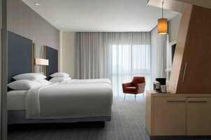 A modern hotel room with a large bed, a desk, and a chair.