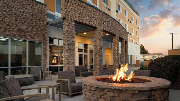 An outdoor seating area with stone pillars, a fire pit, and wicker furniture.