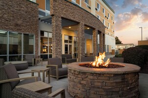 An outdoor seating area with stone pillars, a fire pit, and wicker furniture.