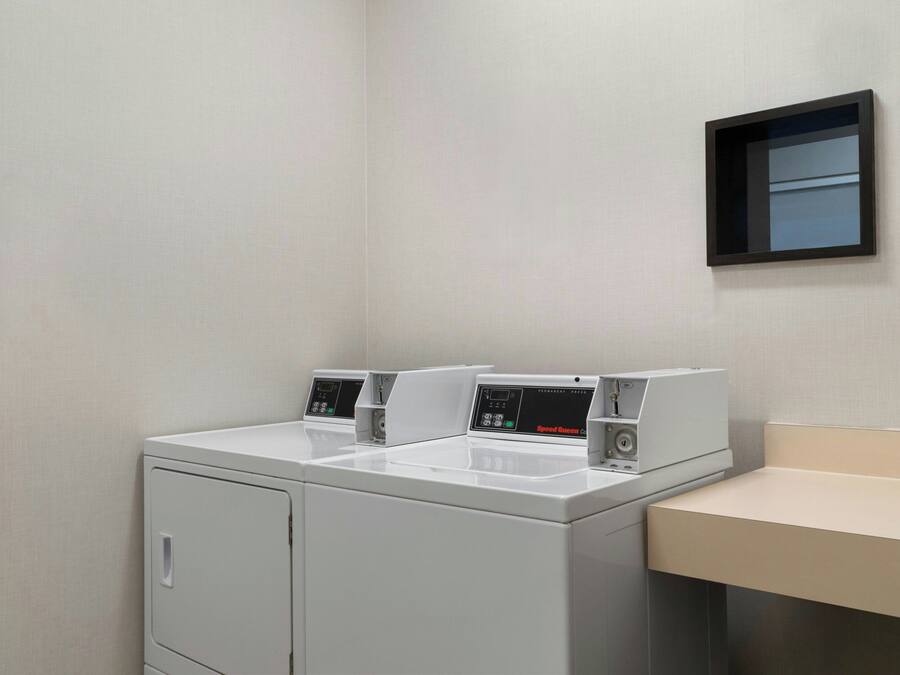 A compact laundry area with two washing machines and a small sink.