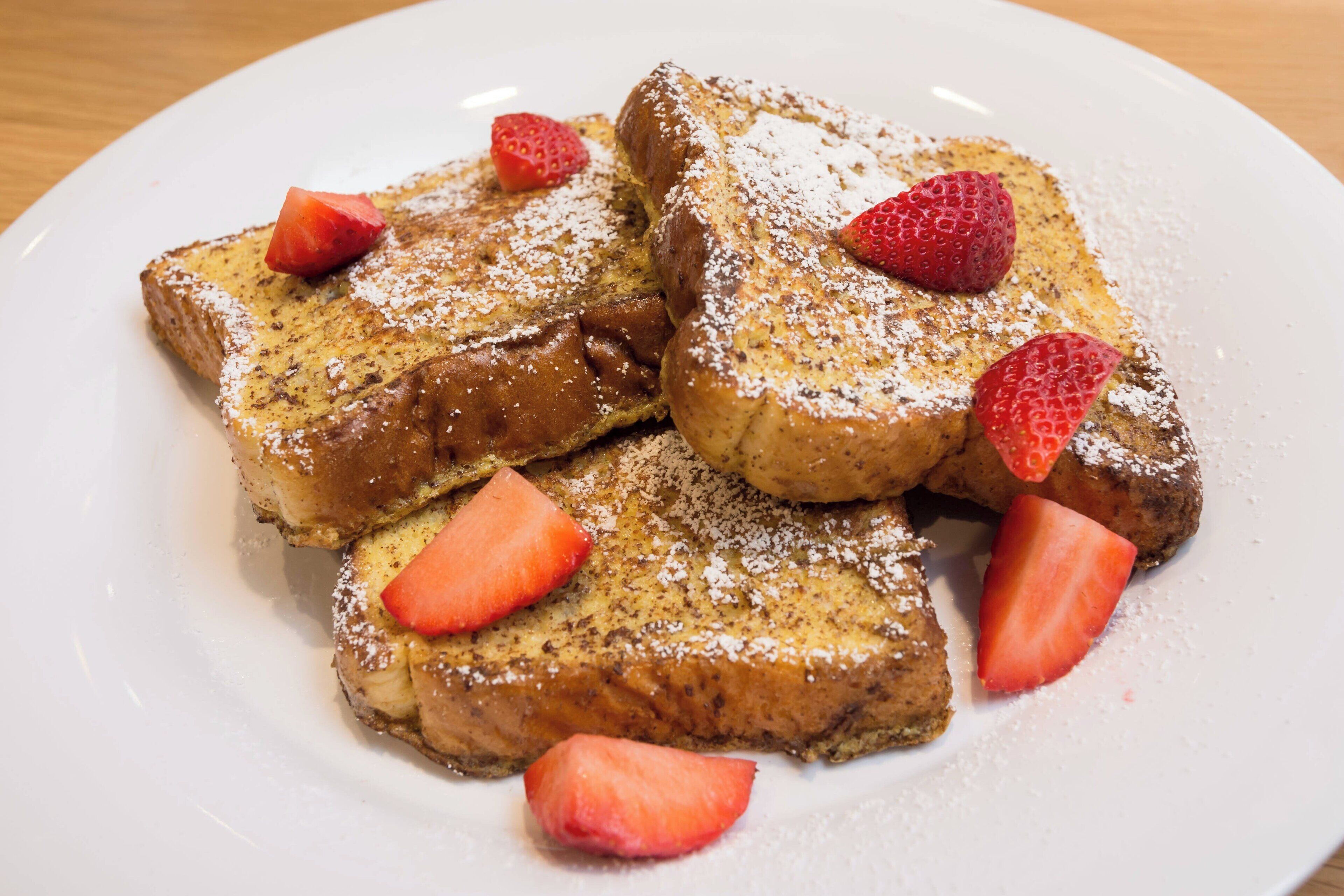 A plate of French toast with strawberries and powdered sugar.