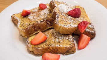 A plate of French toast with strawberries and powdered sugar.