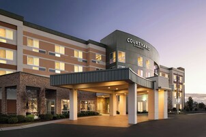 Un hotel Courtyard by Marriott con diseño moderno, que cuenta con una entrada cubierta y varios pisos.