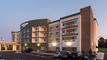 A Courtyard Marriott hotel with multiple floors, a parking lot, and a brick accent wall.