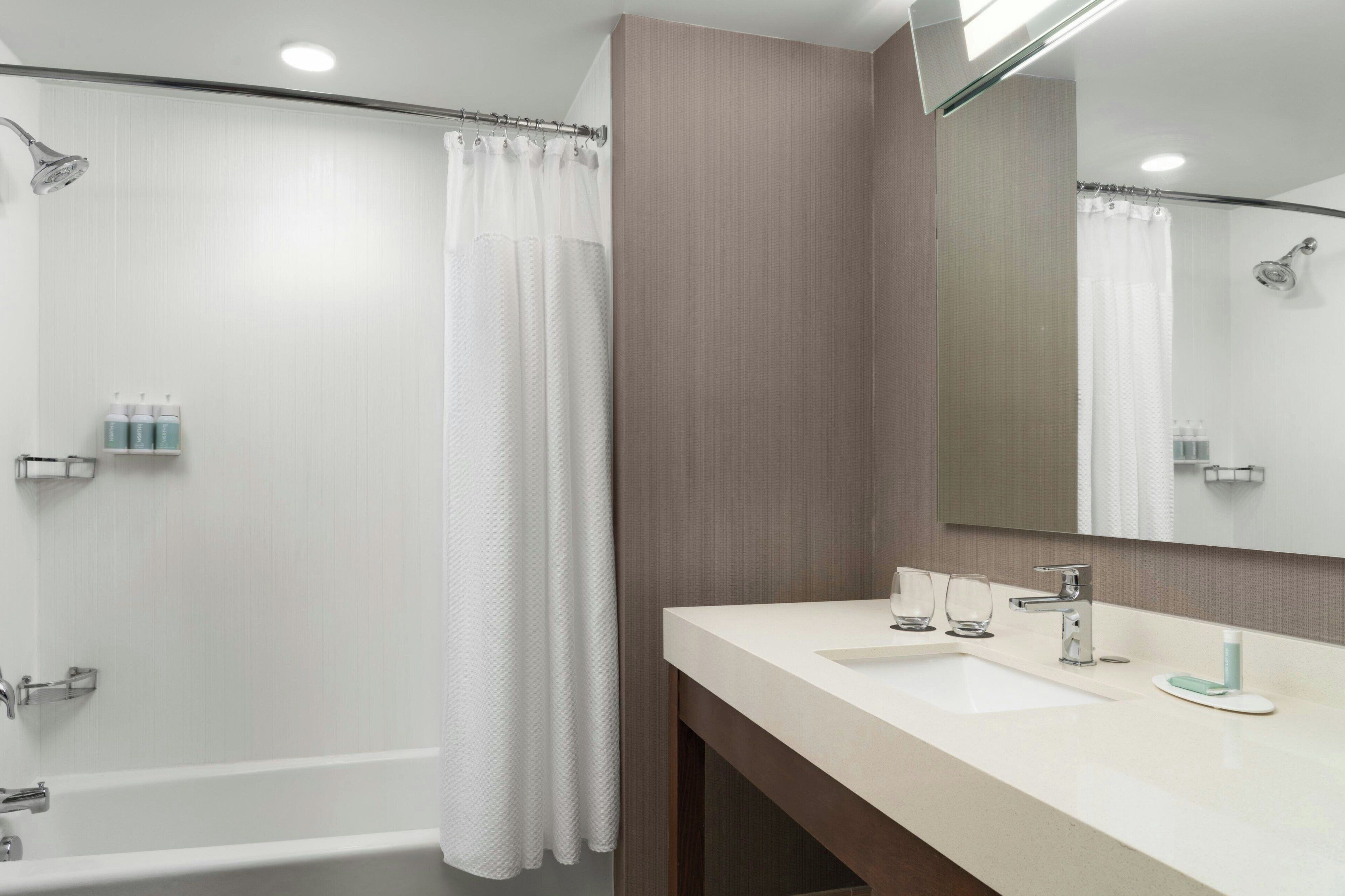 Un bagno moderno con vasca, doccia e un mobile lavabo con lavandino e specchio.