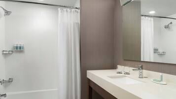 Un bagno moderno con vasca, doccia e un mobile lavabo con lavandino e specchio.