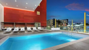 A modern indoor pool with white lounge chairs and a red wall. - Courtyard by Marriott Santa Monica (Santa Monica)