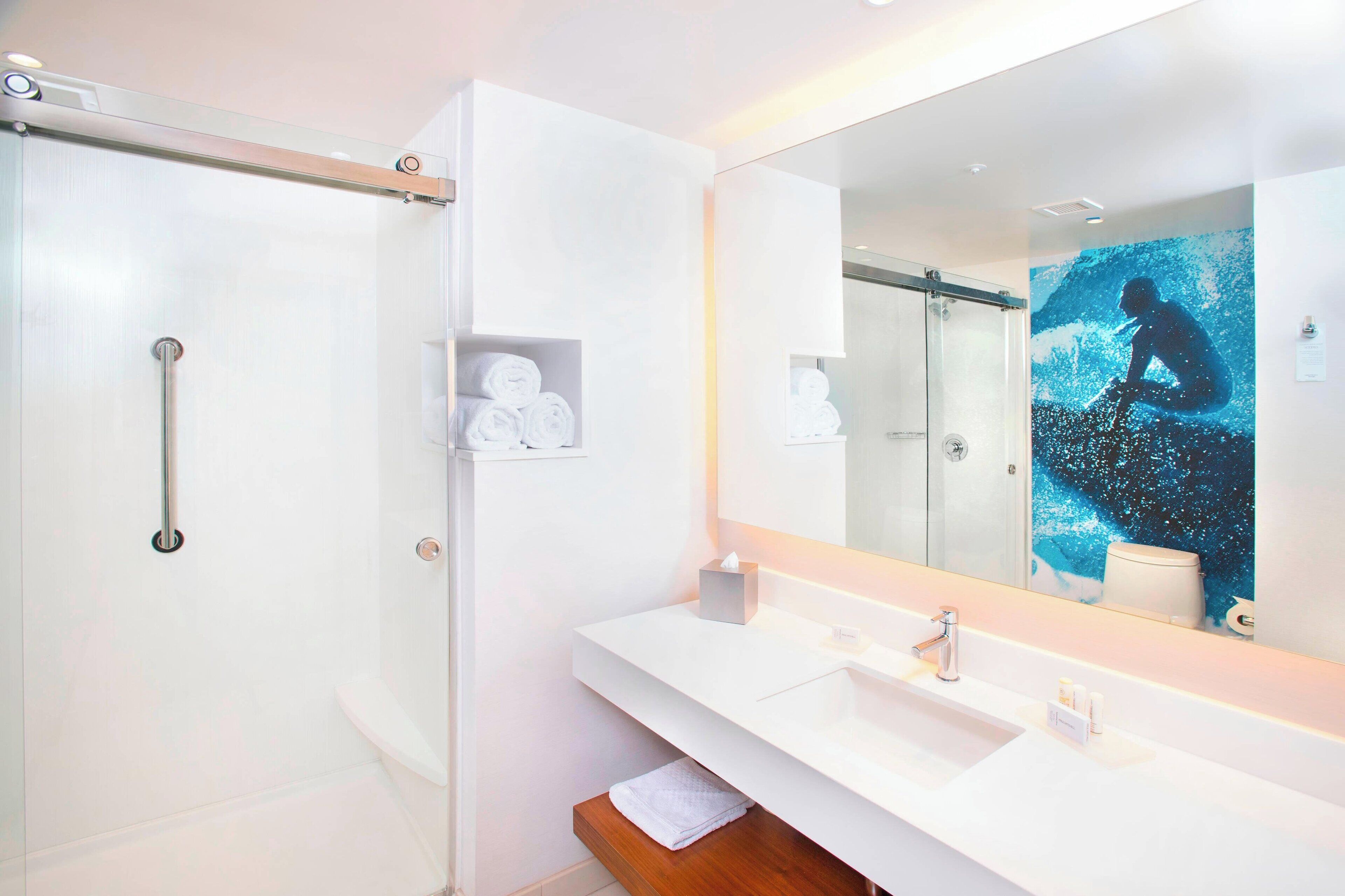A modern bathroom with a glass shower enclosure, a white sink with a mirror, and a towel rack.