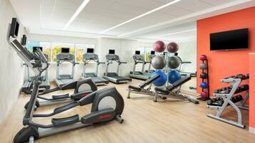 A gym with treadmills, elliptical machines, and various exercise equipment.