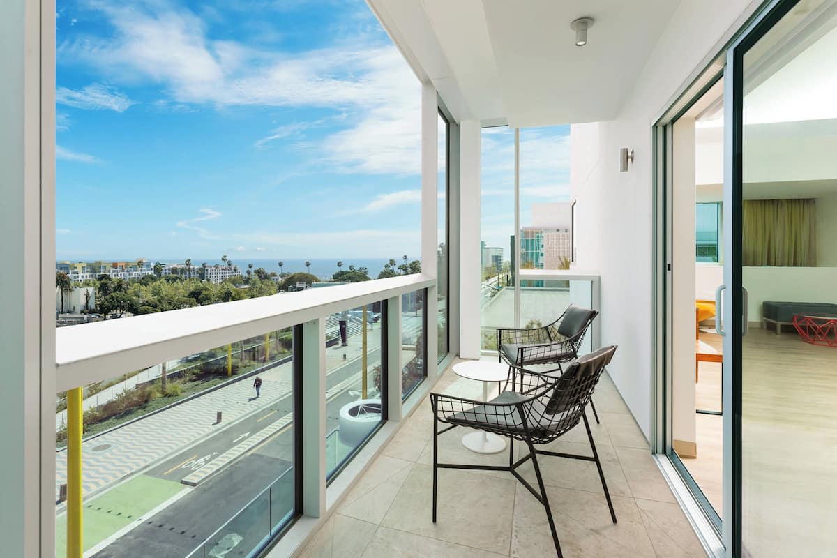 A balcony with a view of the city and ocean, featuring a table and chairs.
