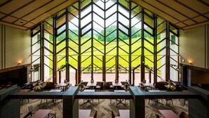 A spacious interior with large windows, a high ceiling, and a view of a green landscape.