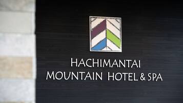 A sign for Hachimantai Mountain Hotel & Spa with a logo above the name.