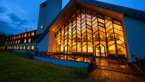 A modern building with a large glass facade and a wooden deck in front.