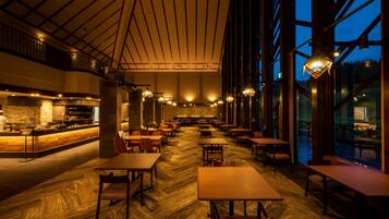 Een ruime eetzaal met hoge plafonds, grote ramen en een bar in het midden.