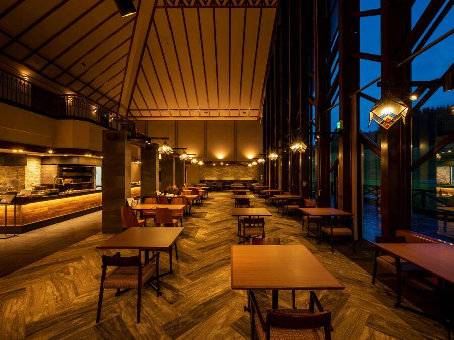 Een ruime eetzaal met hoge plafonds, grote ramen en een bar in het midden.