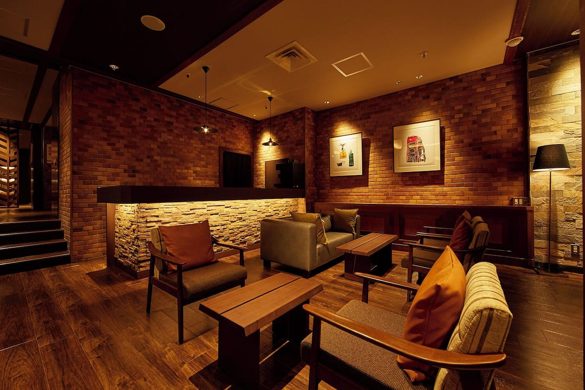 Un espace salon accueillant avec un mur en briques, un plancher en bois et des sièges confortables.